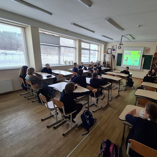 Mokiniai diskutuoja klasės suoluose.