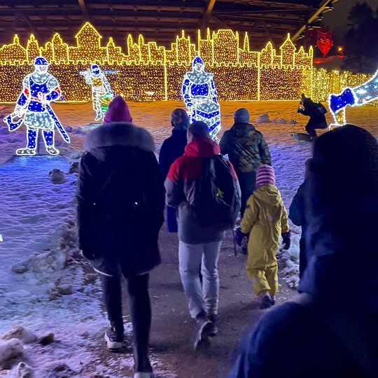 Vaikų grupė keliauja estrados link. Aplink juos yra pilies sargų instaliacijos.