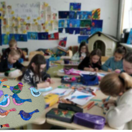 Vaikai dirba klasėje. Nuotraukos kairiame kampe pavaizduoti nuspalvoti mediniai paukštukų siluetai.