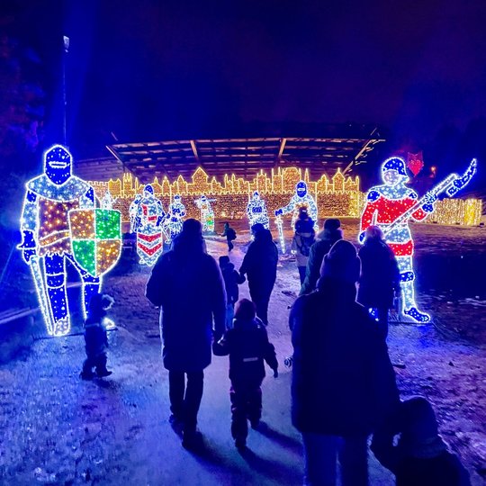 Žmonės eina instaliacijomis papuoštu Kalnų parko taku. Instaliacijose - pilies sargai, kariai.
