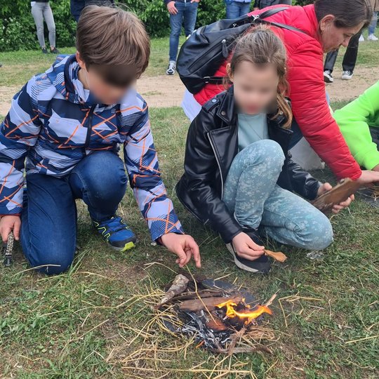 Pora mokinukų rūpinasi savo įkurta ugnele ir stengiasi, kad ji neužgestų.