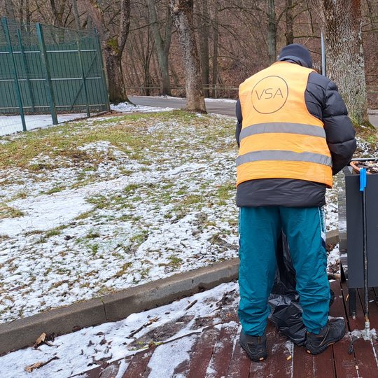 Rezervato tvarkytojas renka šiukšles iš lauko vazonų, esančių prie Bike Wash lauko kavinės.