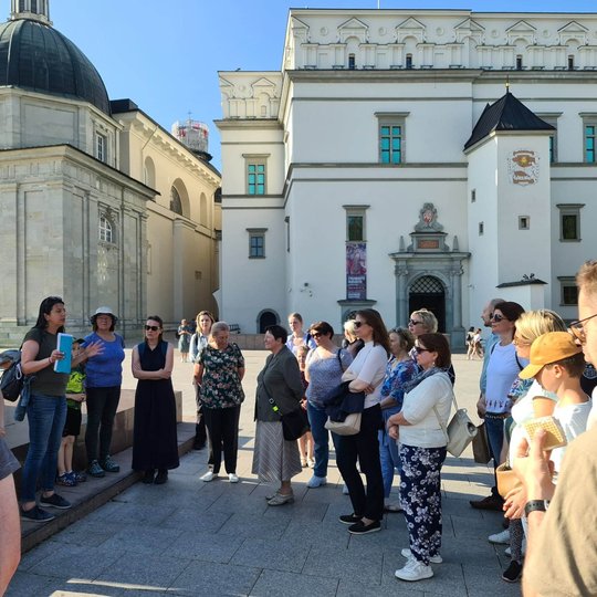 Ekskursijos dalyviai pavėsyje bando įminti Pilių paslaptis - apie tai padeda aiškintis gidė.