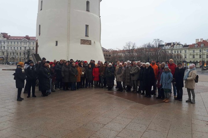 Būrys žmonių stovi prie Katedros varpinės.