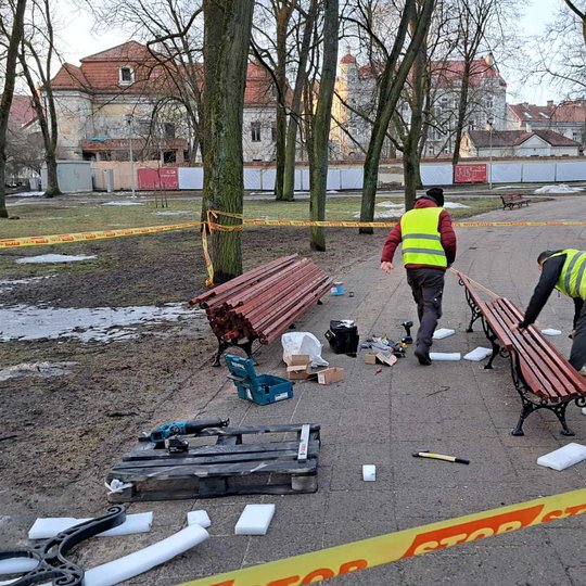 Du meistrai montuoja atnaujintus lauko suolus parke.