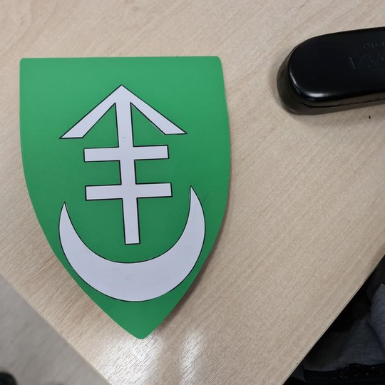 Ant stalo padėtas žalias, mokinio pagamintas herbas.