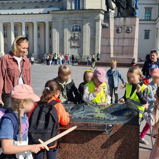 Mokinukai nagrinėja, žiūrinėja ir čiupinėja Vilniaus Aukštutinės ir Žemutinės pilių maketą Katedros aikštėje.
