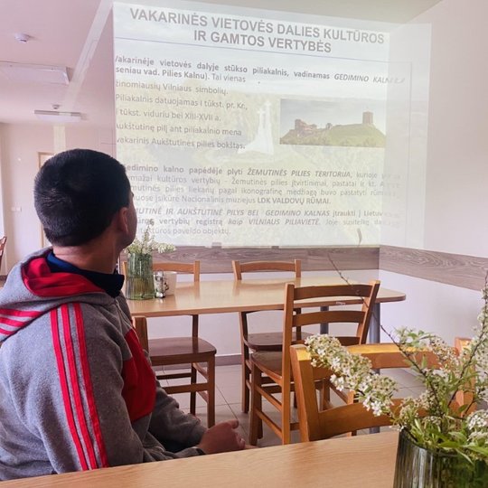 Vienas globos namų gyventojas stebi paskaitą, rodomą per projektorių.