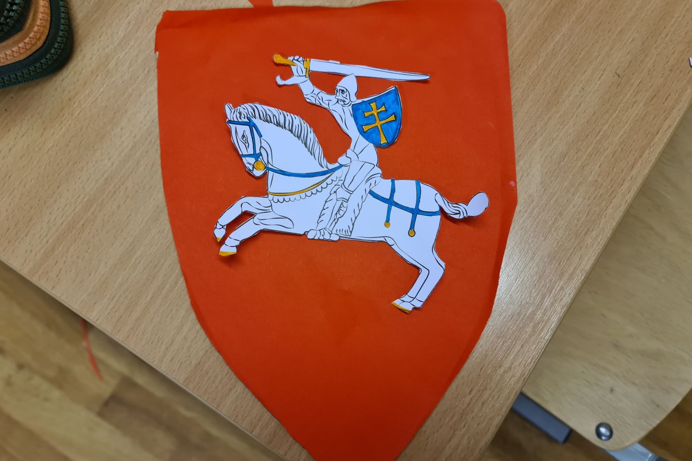 Vaikų gamintas Vyčio herbas ant klasės stalo.