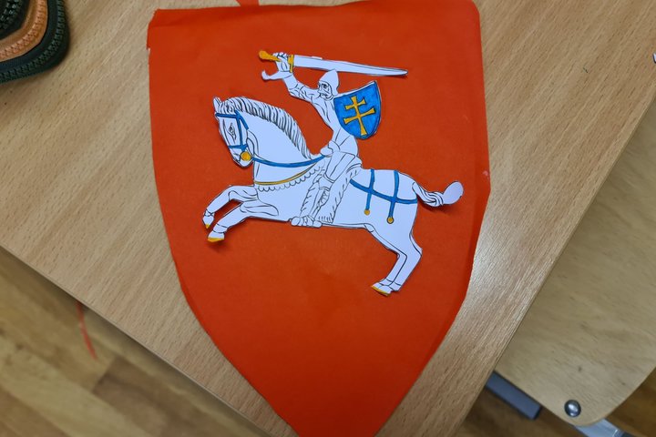 Vaikų gamintas Vyčio herbas ant klasės stalo.