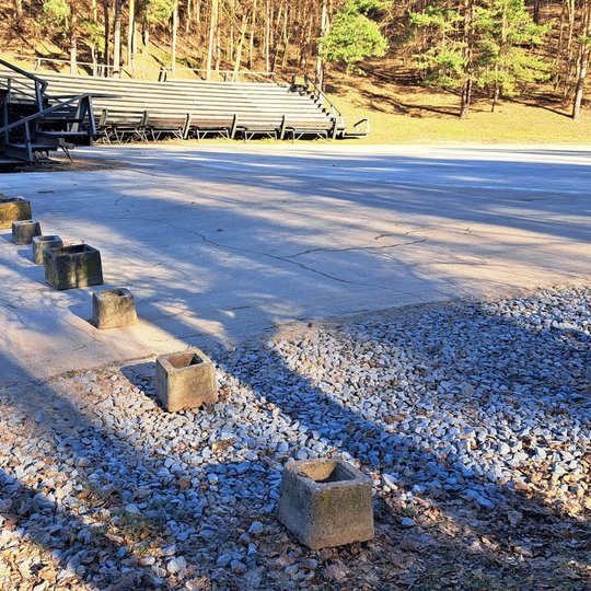 Nuotraukoje betoniniai lauko vazonai, pastatyti per estrados įvažiavimą.