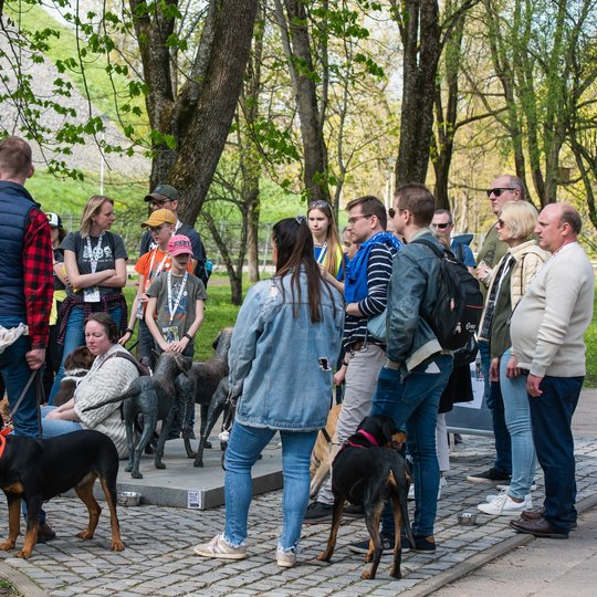 Renginio dalyviai prie skalikų skulptūros Pilių parke, kartu ir su savo augintiniais.