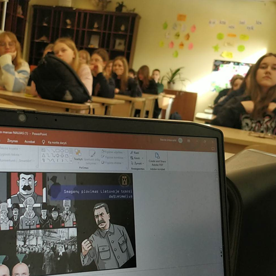 Nuotraukoje matyti aštuntokai, įdėmiai žiūrintys edukatorės rodomas skaidres apie "Roko maršo" laikus.