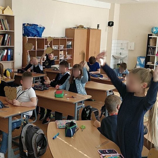 Mokiniai klasėje kūrė savo laikrodžius iš kartono. Nuotraukoje jie vaizduojami iškėlę savo laikrodžius.