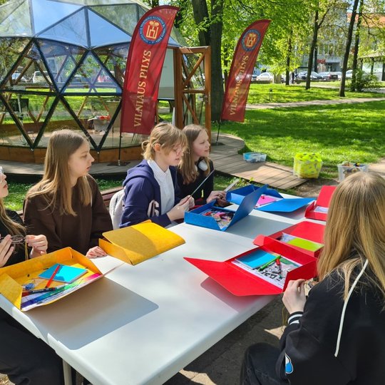 Mokiniai prie dirbtuvių stalo Pilių parke su "tyrėjų" įrankiais segtuvuose.