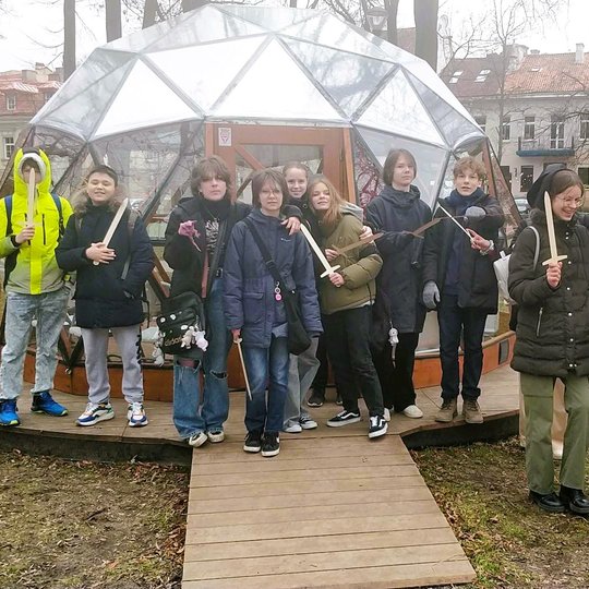Nuotraukoje mokiniai, po ekskursijos, apdovanoti kardais, pozuoja prie Vilniaus pilių kupolo.