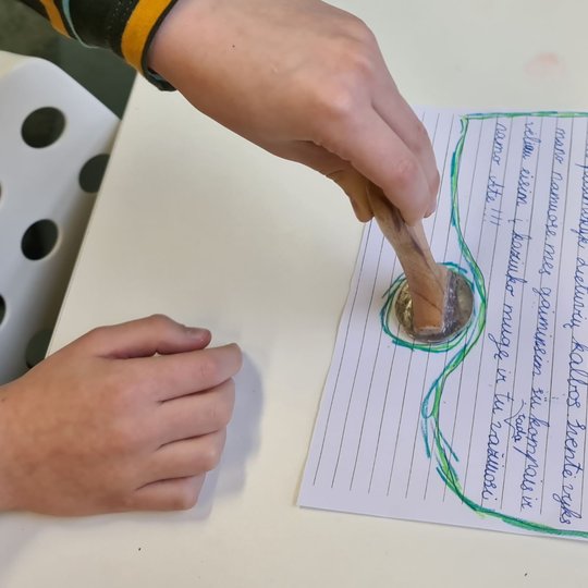 Vaikas deda antspaudą ant savo rašyto laiškelio Gediminui.