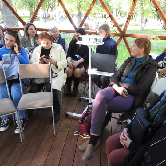 Docentė daktarė Žydrūnė Miliauskienė (centre) skaito paskaitą tarp susirinkusių klausytojų, sėdinčių ant kėdžių kupole.