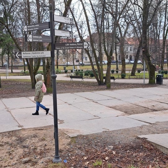 Nufotografuotas stulpas su nukreipiamosiomis rodyklėmis Sereikiškių parke, Gedimino pilies kalno pietinėje papėdėje.