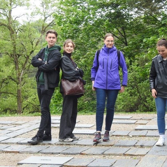 Studentai besišypsodami pozuoja ant Karigailos kalvos, prie Gedimino genealoginio medžio.