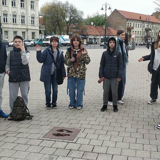 Mokiniai, prie Katedros aikštėje esančios "pėdų" plytelės.