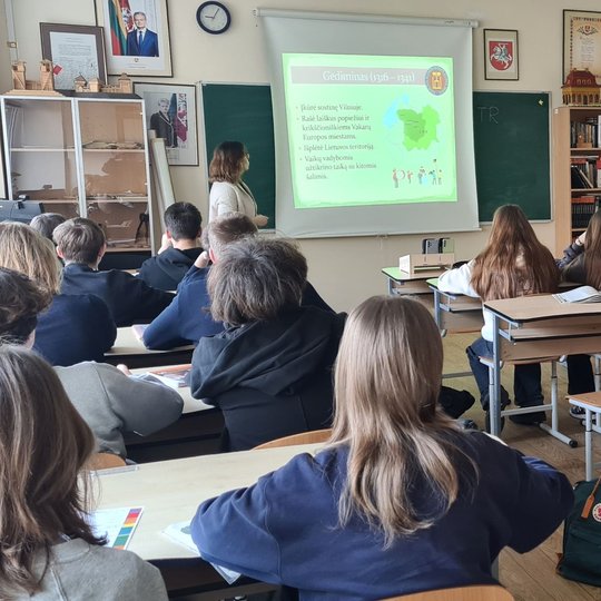 Aštuntokai sėdi klasėje ir klausosi edukatorės pasakojimo apie Gediminą.
