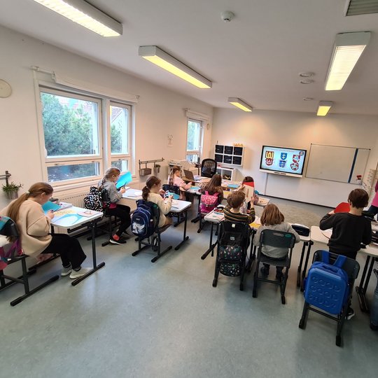 Mokiniai rašo laiškus klasėje.