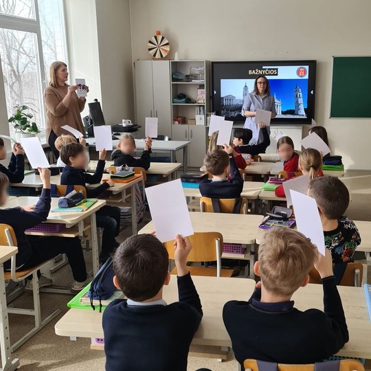 Trečiokai klasėje iškėlę baltus lapus į viršų.