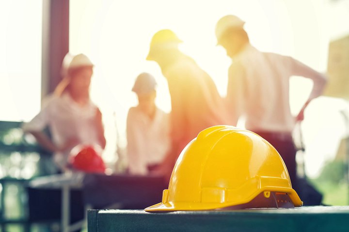 Asociatyvinė nuotrauka, vaizduojanti darbininko šalmą ir projektuotojų siluetus.