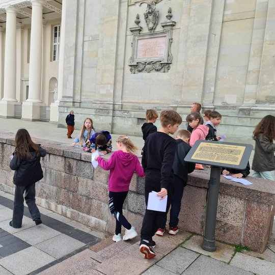 Ketvirtokai, žaisdami prie Valdovų rūmų informacinio stendo, mokosi pažinti Vilniaus pilis.
