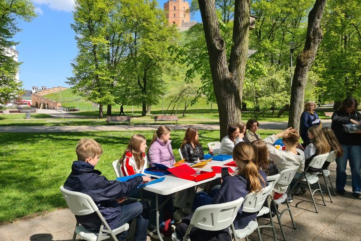 Mokiniai įsitaisė prie stalo dirbtuvėms Vilniaus pilių parke.