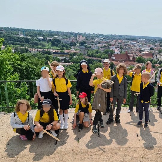 "Žiniukai" su mediniais kardais stovi Trijų kryžių kalno aikštelėje.