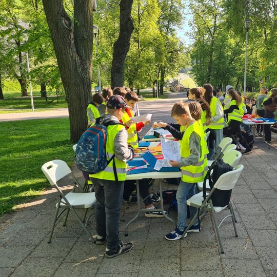 Mokiniai kyla nuo stalų, apsirengę atšvaitines liemenes.