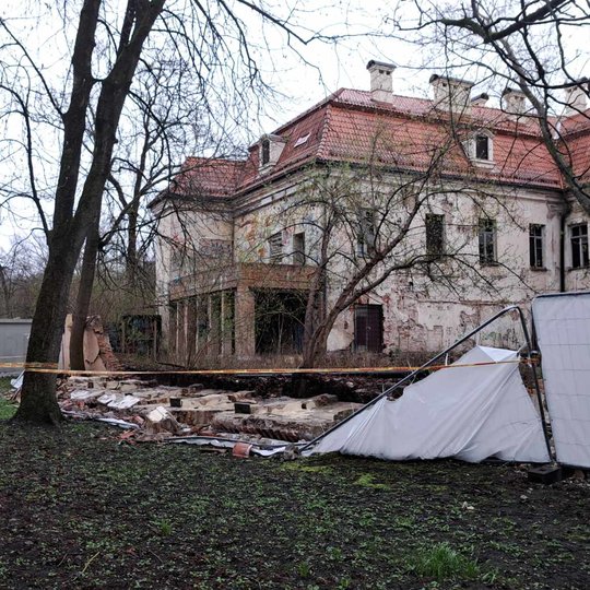 Nufotografuota nuvirtusi Kirdiejų rūmų tvora iš dešiniojo šono. Teritorija aptverta stop juosta.