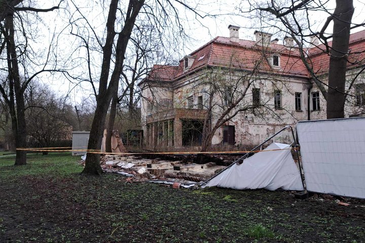 Nufotografuota nuvirtusi Kirdiejų rūmų tvora iš dešiniojo šono. Teritorija aptverta stop juosta.