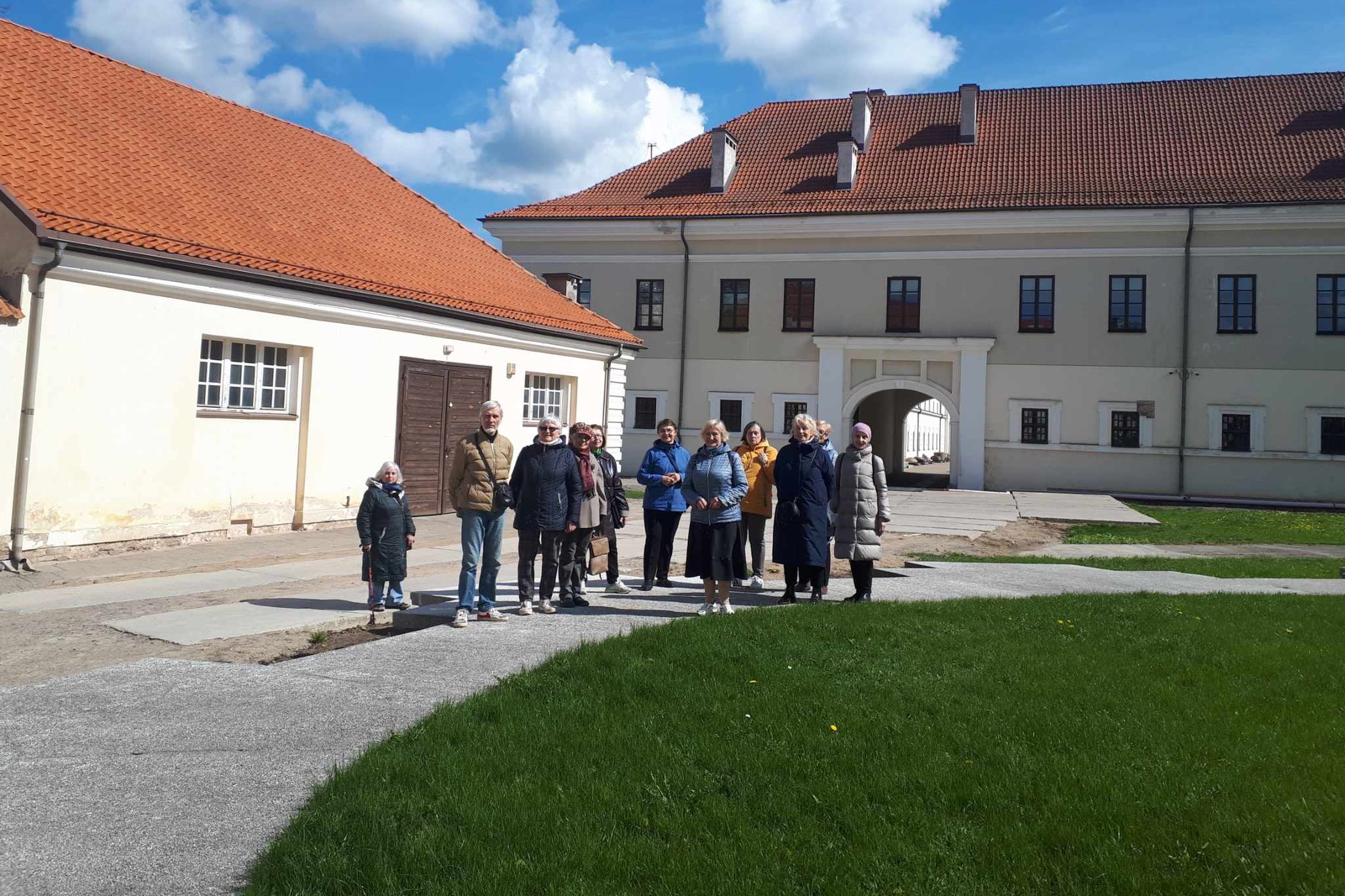 Trečiojo amžiaus universiteto studentai nufotografuoti muziejaus kieme, prie buvusios bažnyčios pamatų.