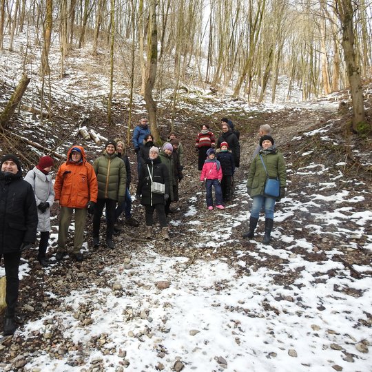 Ekskursijos dalyviai pozuoja nuotraukai kalno šlaite. Jiems už nugaros kalnas, apaugęs medžiais.
