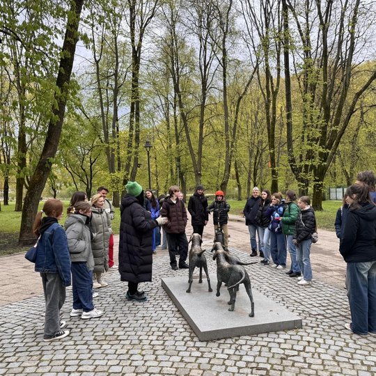 Turistų grupė su gide Sereikiškių parke, prie Lietuviškų skalikų skulptūros.