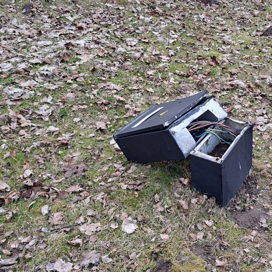 nufotografuota nuversta į šoną elektros skydinė. iš jos išlindę elektros laidai.