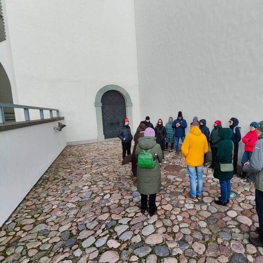 Gide Nerilė ekskursantams pasakoja apie Lietuvos valdovų meilės istorijas, šalia Valdovų rūmų pietinių vartų.