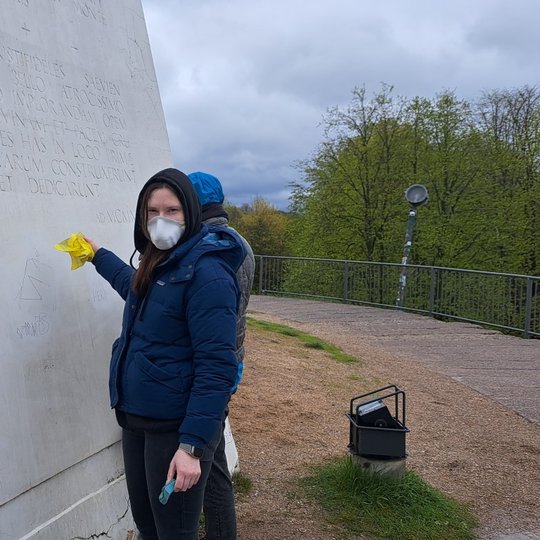 Dvi savanorės valo vandalų markerių užrašus nuo Trijų Kryžių paminklo.