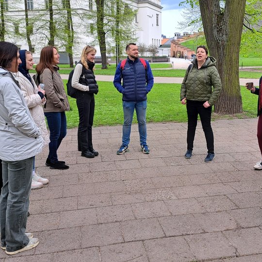 Po pikniko savanorius pasitiko gidė. Nuotraukoje visi savanoriai su gide stovi rateliu.