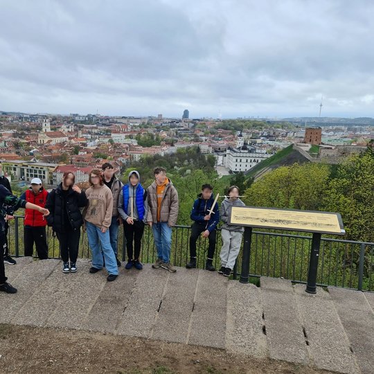 Mokiniai su mediniais kardais rankose ant Trijų Kryžių kalno apžvalgos aikštelės.