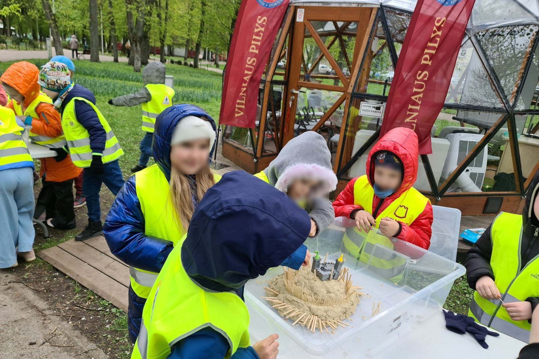 Mokinukai prie Vilniaus pilių kupolo stato smėlio pilis.