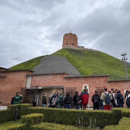 Turistai Bonos Sforcos sodelyje. Virš jų - Gedimino pilies bokštas.