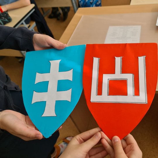Du vaikų pagaminti herbai. Mėlyname herbe matomas Jogailos dvigubas kryžius, raudoname herbe - Gediminaičių stulpai.