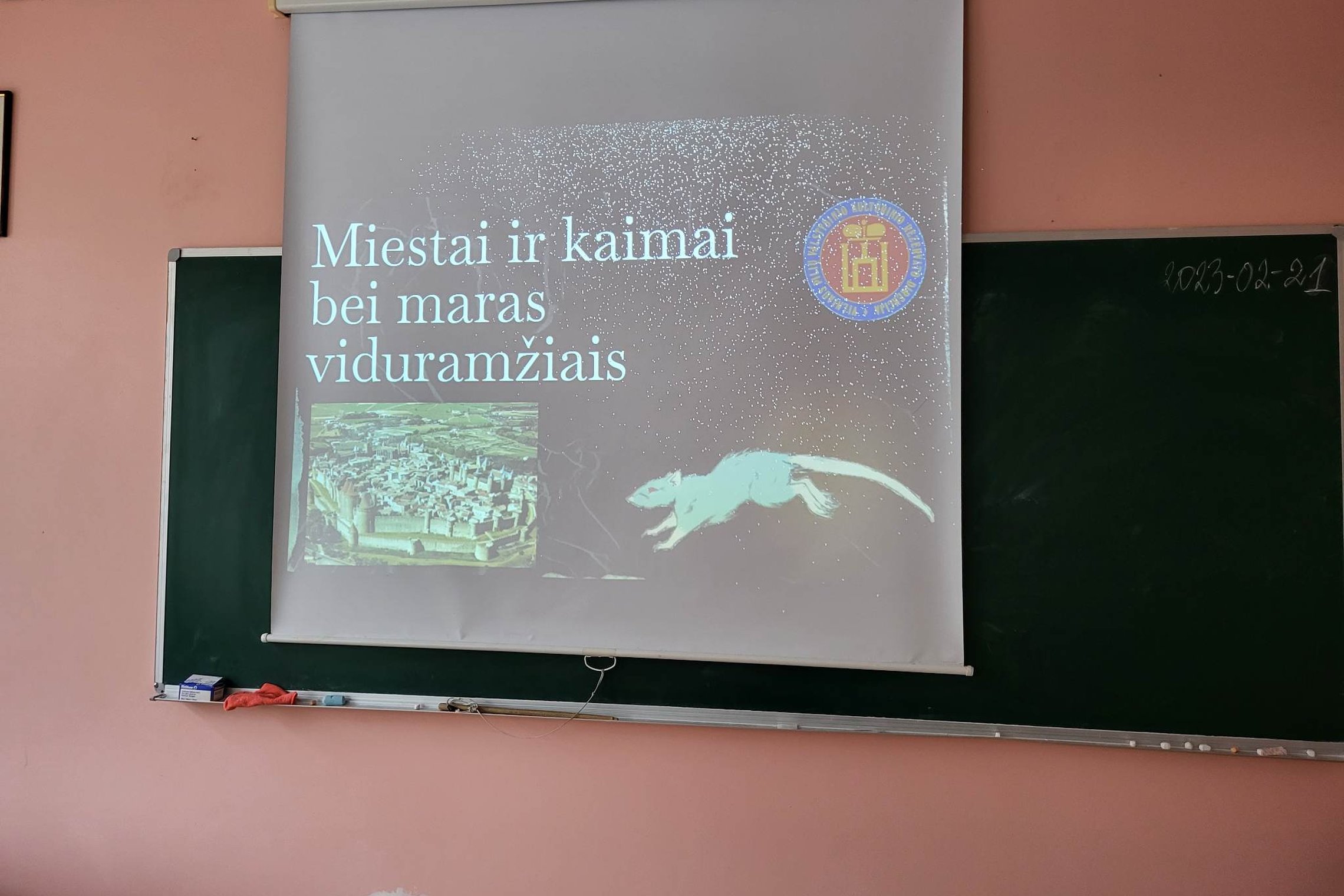 Nuotraukoje - paskaitos mokiniams pirmoji skaidrė klasės lentoje, pavadinimu "Miestai ir kaimai bei maras viduramžiais".