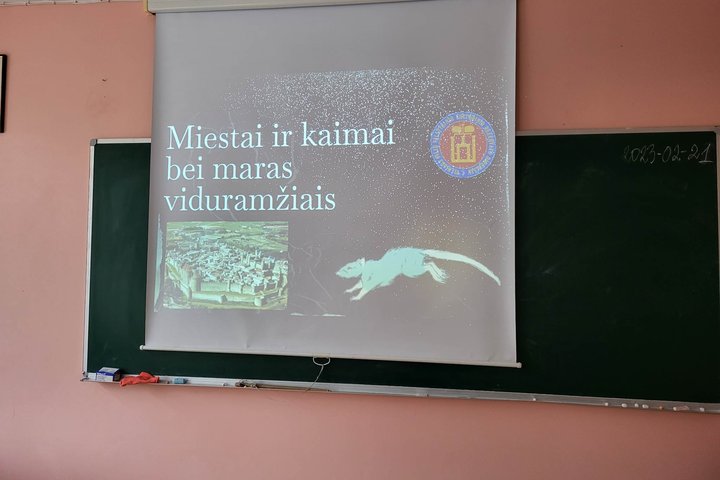 Nuotraukoje - paskaitos mokiniams pirmoji skaidrė klasės lentoje, pavadinimu "Miestai ir kaimai bei maras viduramžiais".