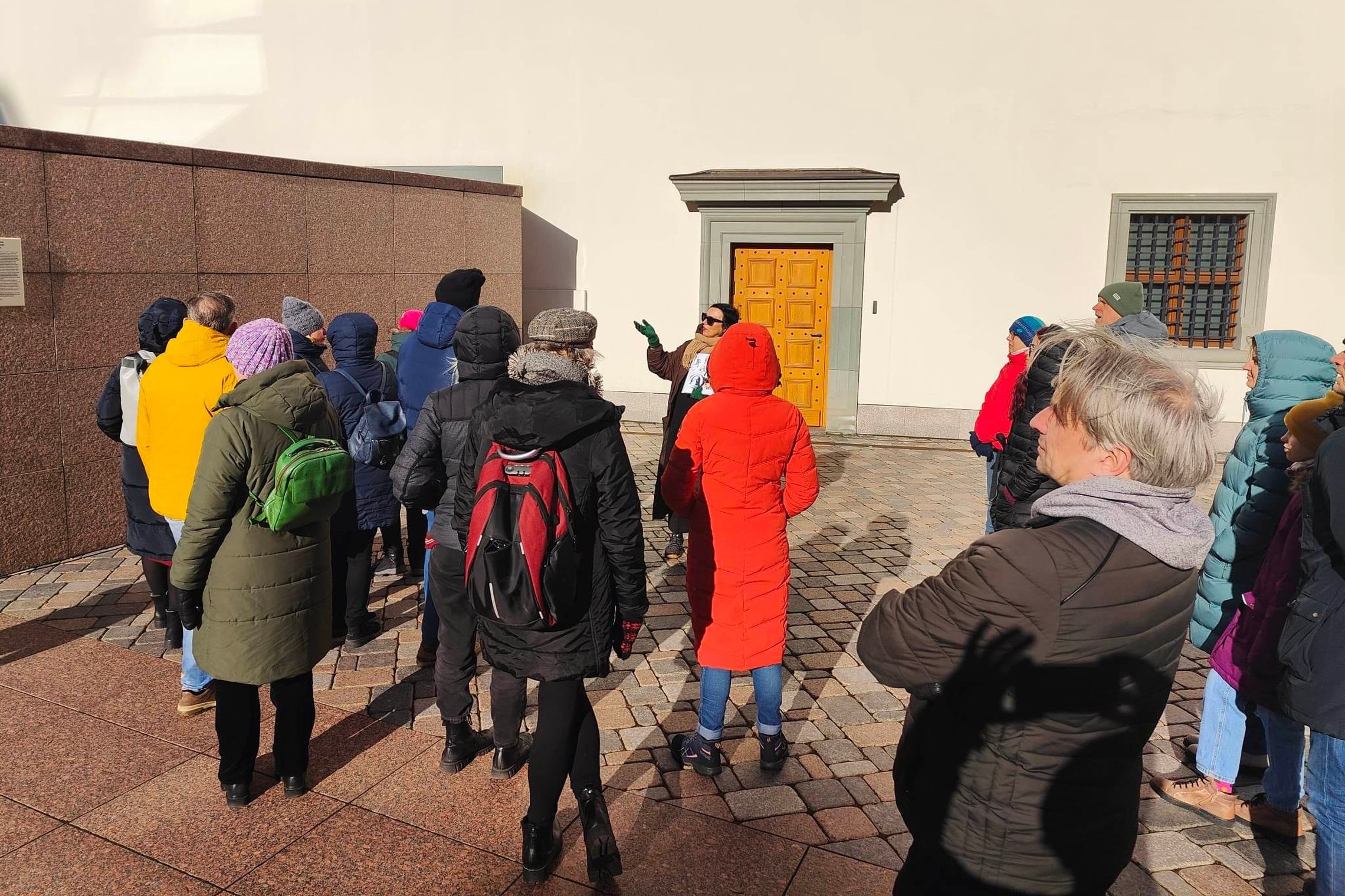 Ekskursijos dalyviai klausosi gidės Valdovų rūmų kieme, šalia tikrojo Gedimino bokšto.