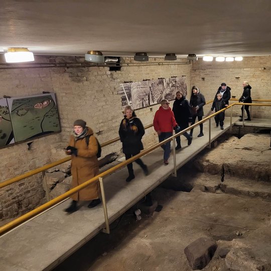 Ekskursijos dalyviai Senojo arsenalo rūsyje apžiūri senuosius pamatus.